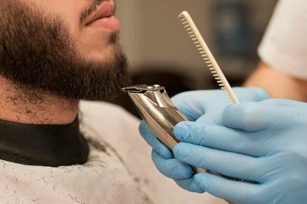 Young man getting his beard styled at the barber