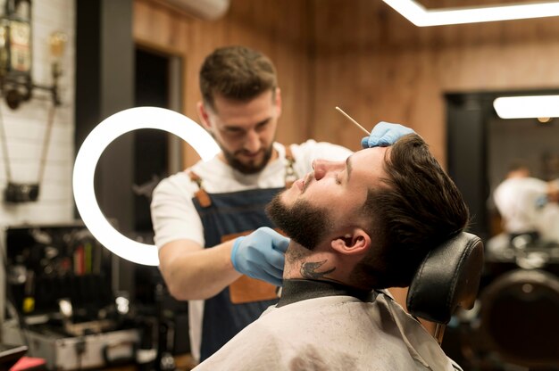 Young man getting his beard styled at the barber