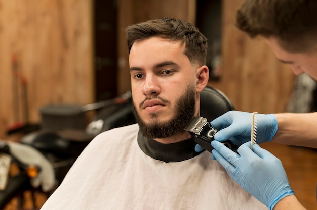 Young man getting his beard styled at the barber