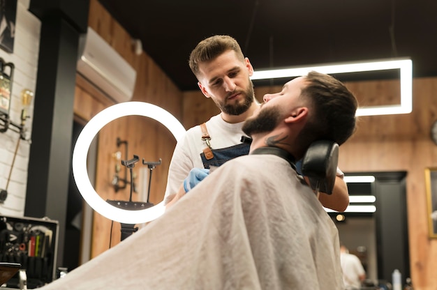 Young man getting his beard styled at the barber