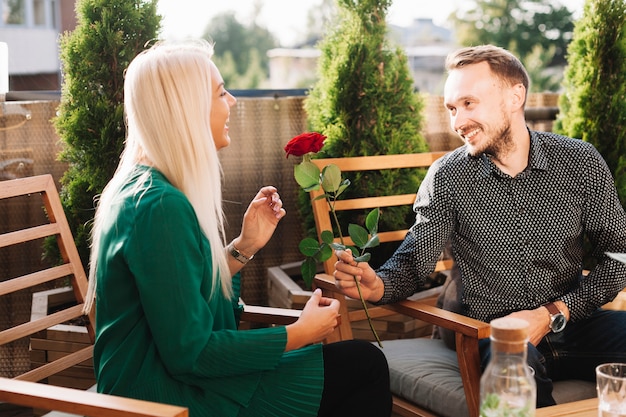 Free photo young man giving beautiful rose to attractive lady