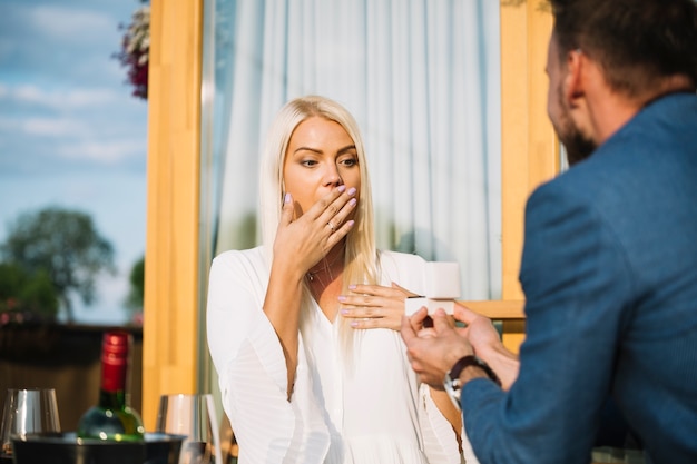 Free photo young man giving engagement ring to attractive surprised lady