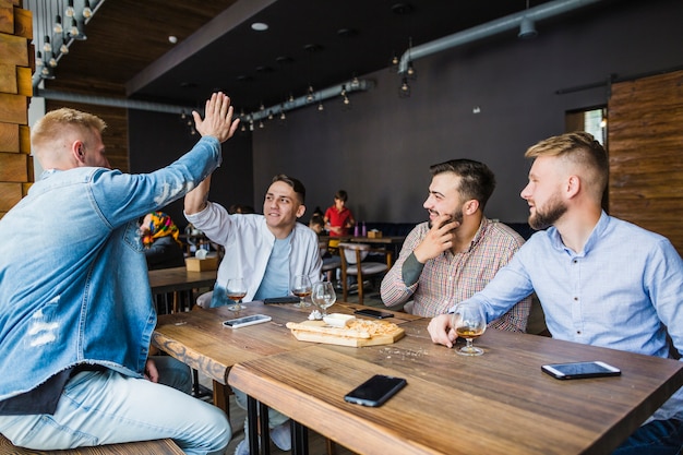 Young man giving high five to his friends in the restaurant