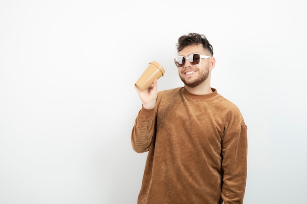 young man in glasses holding cup of coffee. 