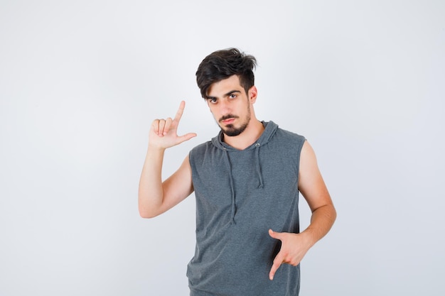 Young man in gray shirt showing gun gestures and looking serious