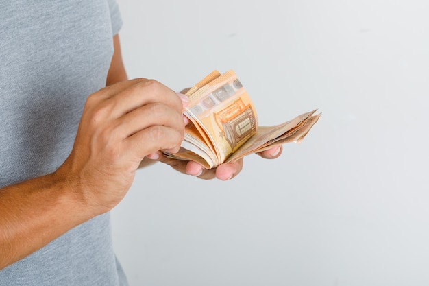 Молодой человек в серой футболке, считая банкноты евро