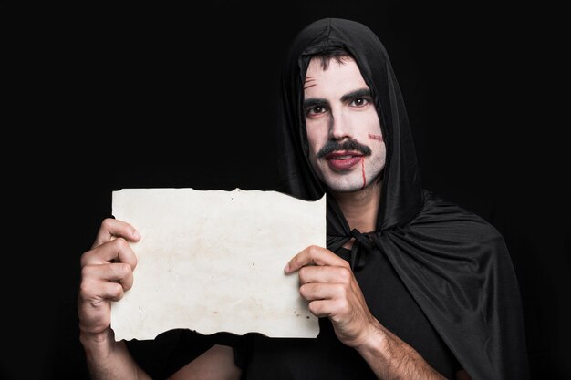 Free photo young man in halloween costume posing in studio with piece of paper
