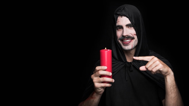 Free photo young man in halloween costume with scratches on face holding candle