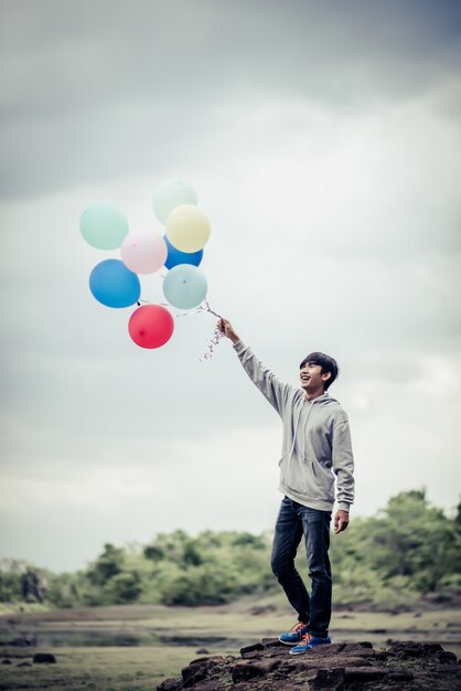 Young man hand holding colorful balloons