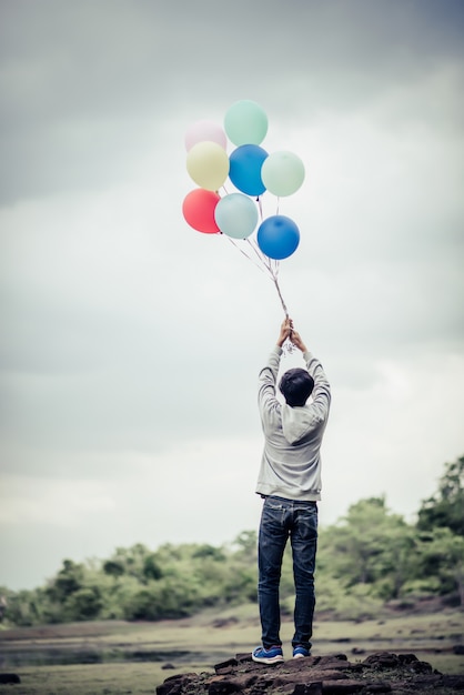 Free photo young man hand holding colorful balloons