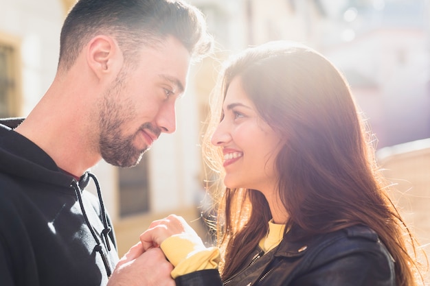 Young man and happy woman holding hands on street