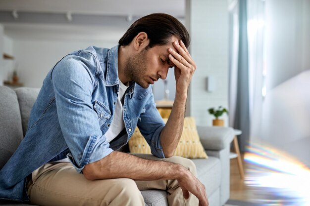 Young man having a headache and holding his head in pain at home