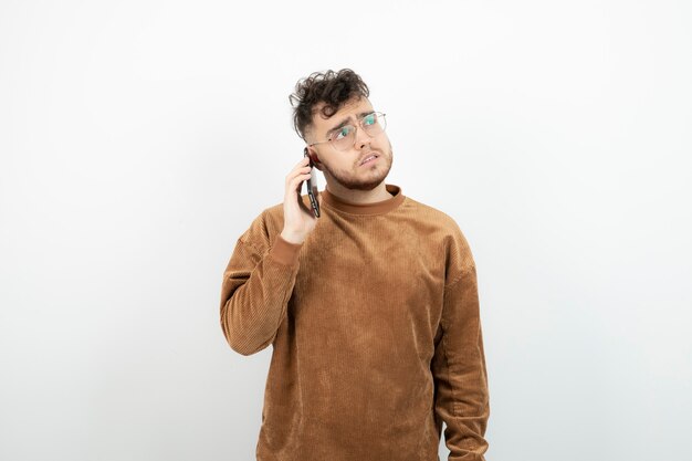 young man having phone call over white wall. 