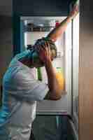 Free photo young man having a snack in the middle of the night at home next to fridge