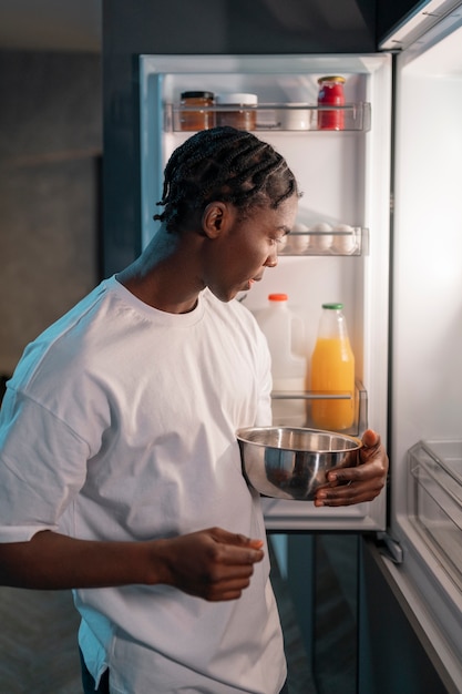 Young man having a snack in the middle of the night at home next to fridge