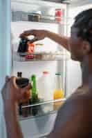 Free photo young man having a snack in the middle of the night at home next to fridge