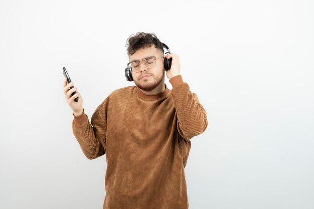 young man in headphones choosing songs on his cellphone. 