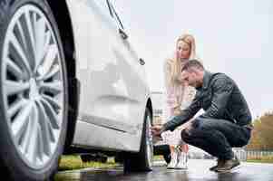 Foto gratuita giovane che aiuta una donna affascinante a riparare la ruota dell'auto