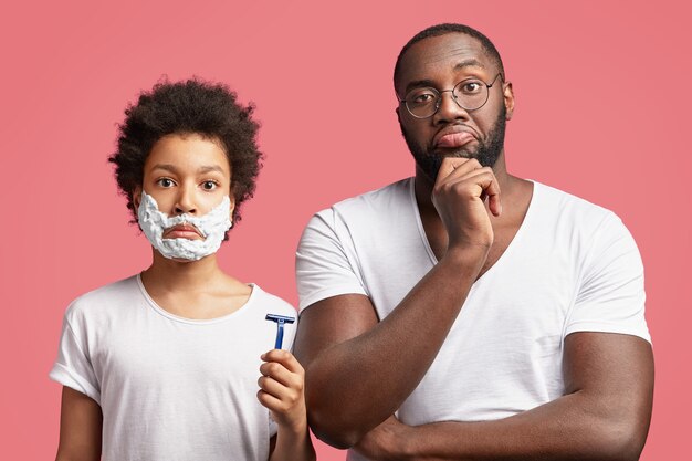 Young man and his son with curly hair holding razor