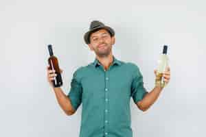 Бесплатное фото Молодой человек держит бутылки алкоголя в рубашке