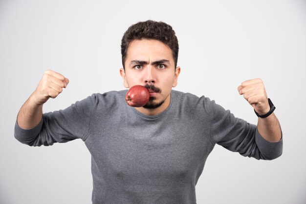 Young man holding apple in his mouth and ready to punch.