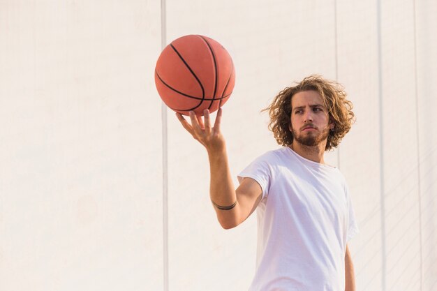 Young man holding basketball against wall