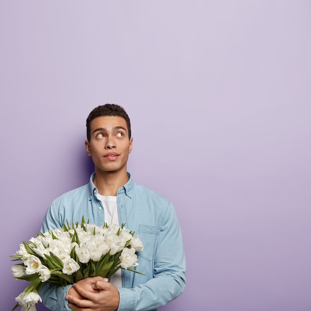 Young man holding bouquet of white flowers