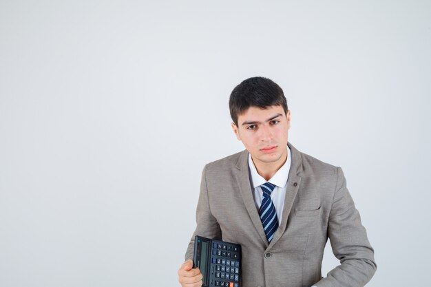 フォーマルなスーツで電卓を保持している若い男