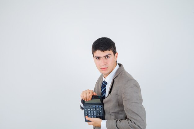 Молодой человек держит калькулятор в строгом костюме