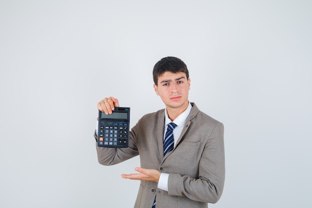 Молодой человек держит калькулятор, протягивая руку, представляя его в официальном костюме