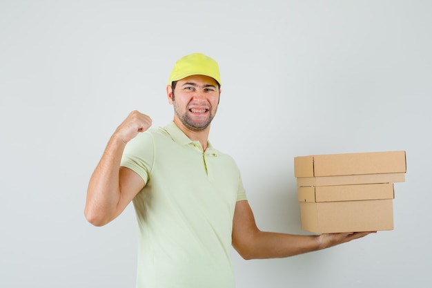 Young man holding cardboard boxes in t-shirt cap and looking blissful  