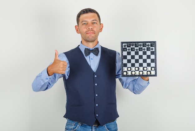 無料写真 若い男がスーツで親指でチェス盤を保持