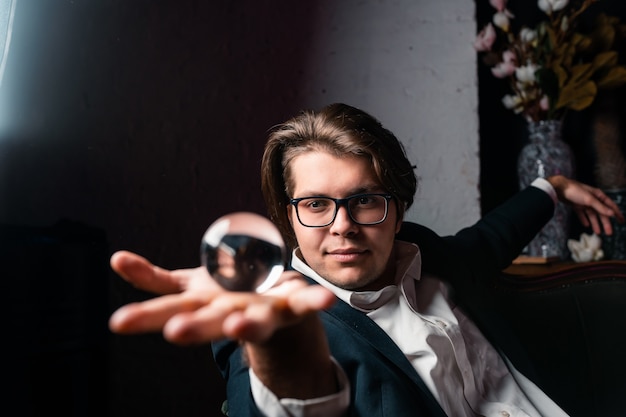 Young man holding a clear transparent crystal glass ball in their hand