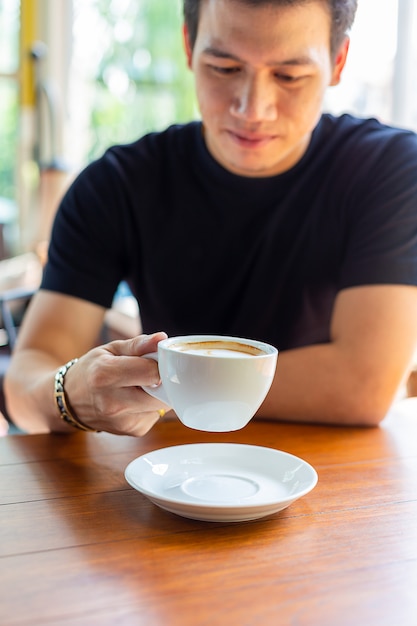 Молодой человек держит чашку горячего кофе
