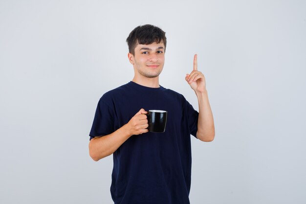 お茶を持って、黒いTシャツを着て、自信を持って見ている若い男。正面図。