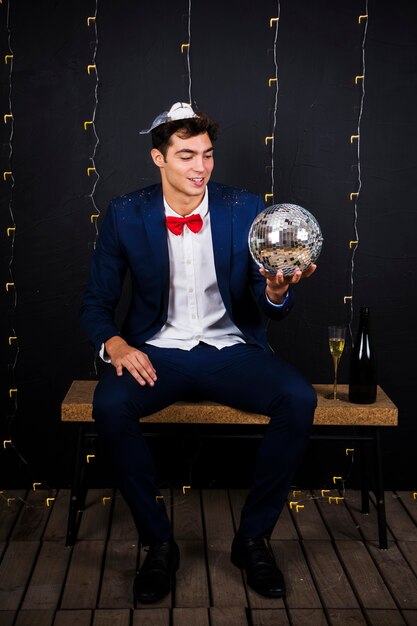 Young man holding disco ball on bench 