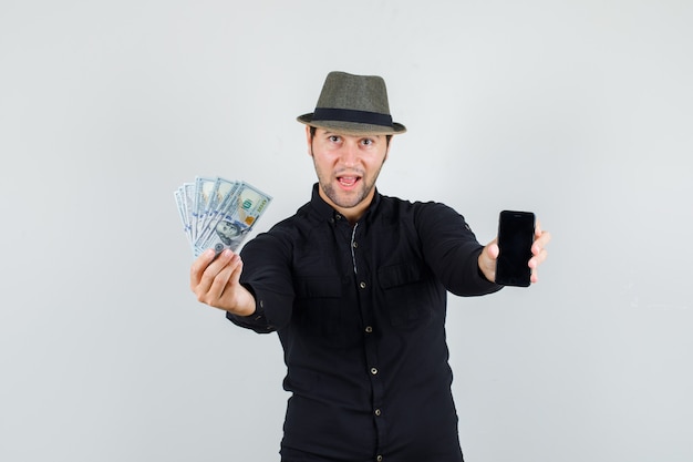 Young man holding dollar bills and smartphone in black shirt