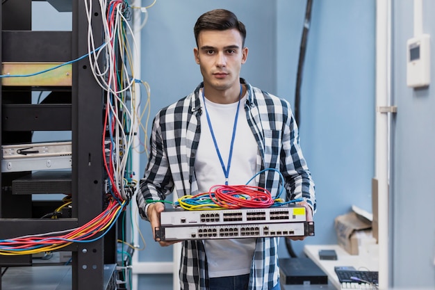 Free photo young man holding ethernet switches and wires