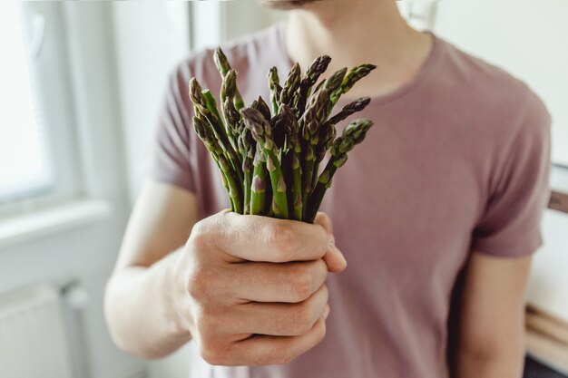 Young man holding fresh asparagus