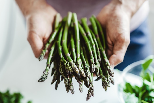 Foto gratuita giovane che tiene asparagi freschi