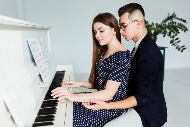 Free photo young man holding hand of her girlfriend for playing piano