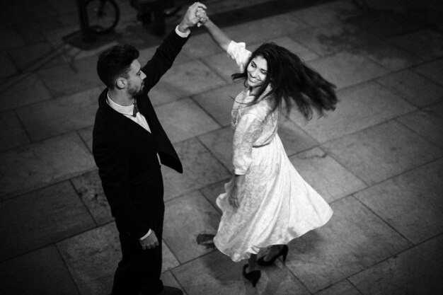 Young man holding hand of whirling elegant cheerful woman