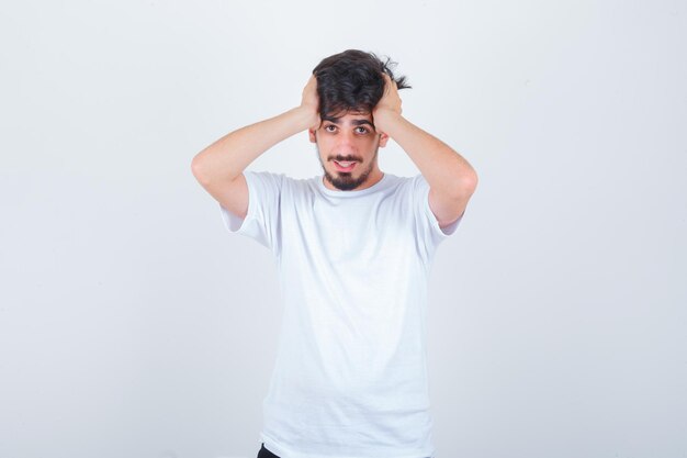Young man holding hands on head in t-shirt and looking forgetful