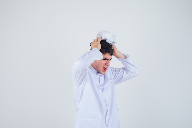 Free photo young man holding hands on head with cap wearing white uniform and looking nervous