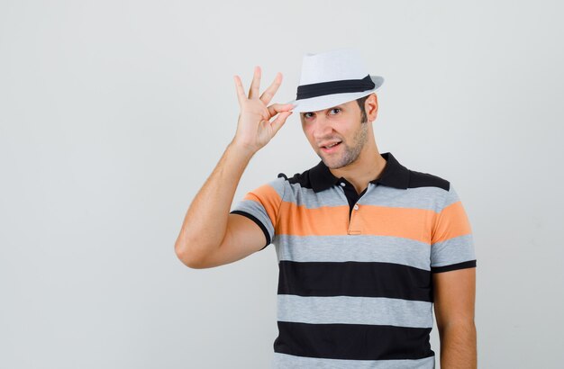 Young man holding his hat in t-shirt,hat and looking cute