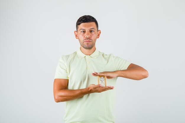 Young man holding hourglass in t-shirt