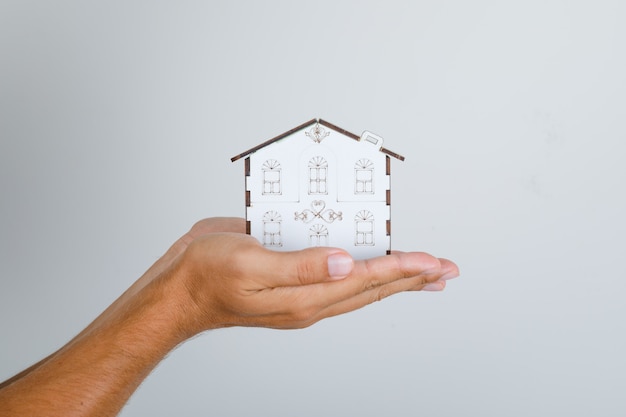 Young man holding house model in his hands.