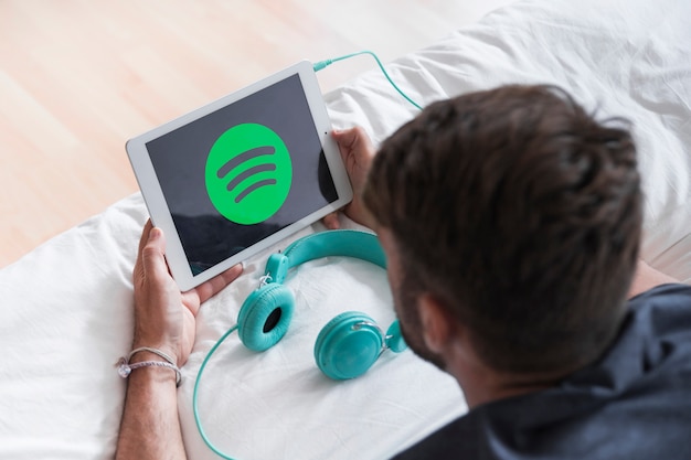 Young man holding modern device with spotify app