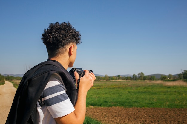 Young man holding modern digital camera