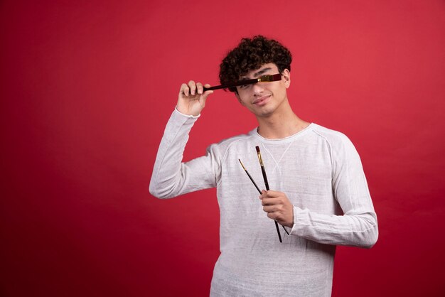 Young man holding paintbrushes  .